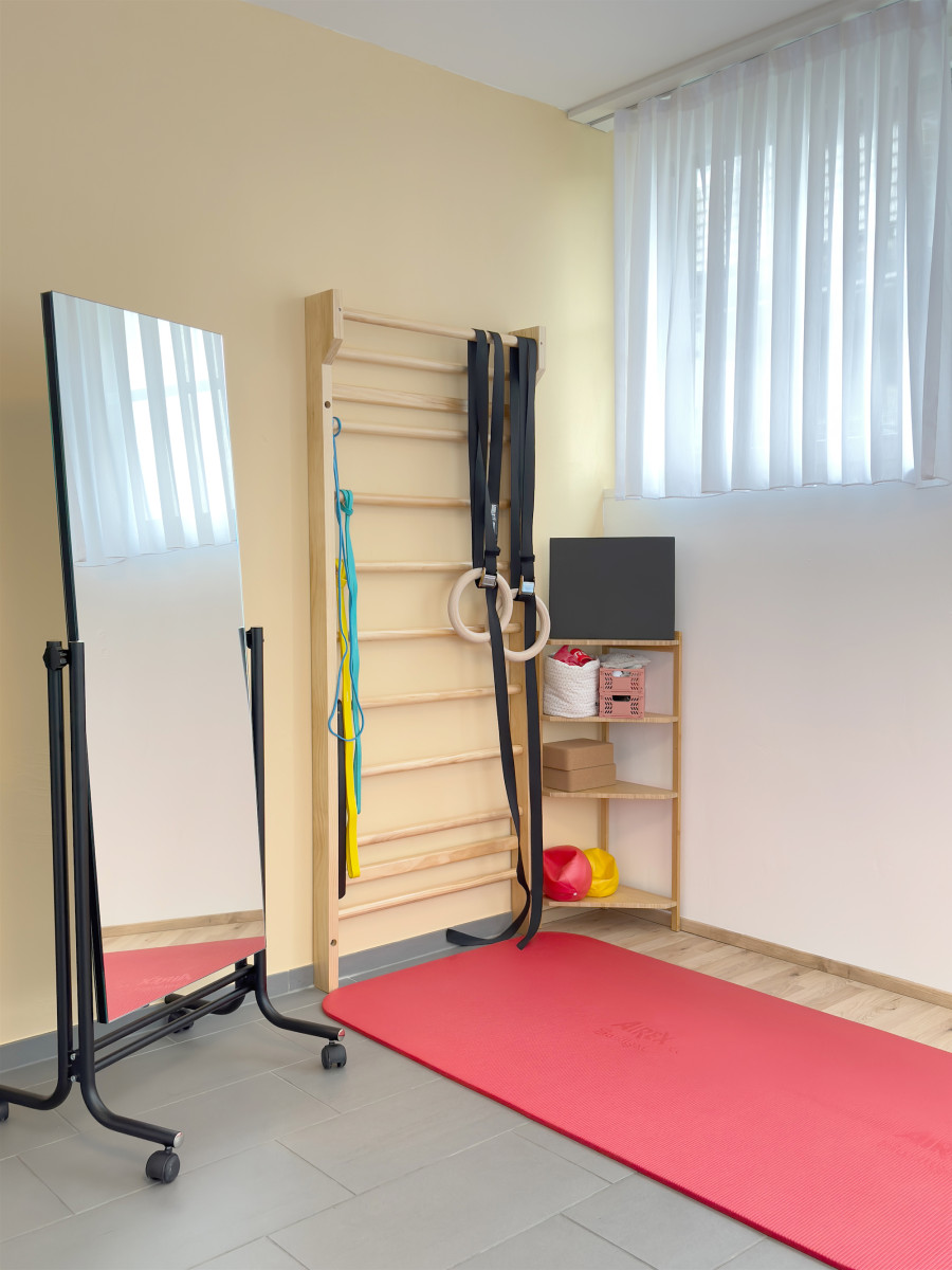 Aktivecke im Behandlungsraum Sprossenwand mit Ringen, Matte und Spiegel für Beckenbodentraining bei Physio am Rank in Zürich Albisrieden und Altstetten